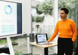 brazilian lady showing chart giving training using laptop and monitor tv in indoors classroom