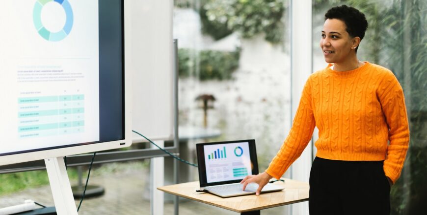 brazilian lady showing chart giving training using laptop and monitor tv in indoors classroom