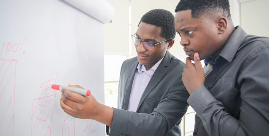 African American young man writing note on a transparent wipe board and thinking of a solution for him work-related problems, Colleagues Having A Business Meeting