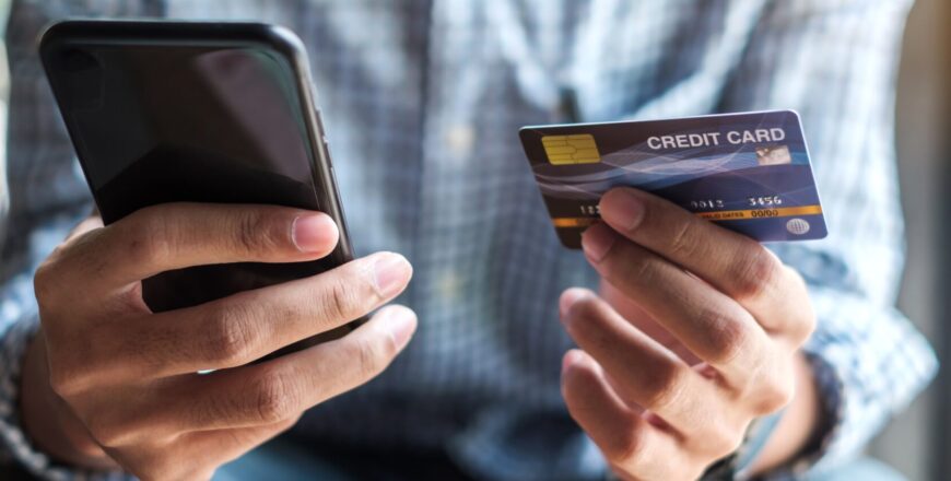 Young casual Business man holding credit card and using touchscr