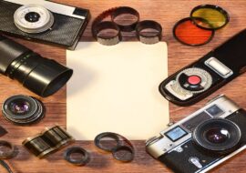 Top View of Vintage photo camera and other old retro photography accessories on wooden table plate with some clear white blank photo frames to placed your pictures or text