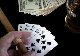 poker playing cards whiskey and some money on a table with reflection