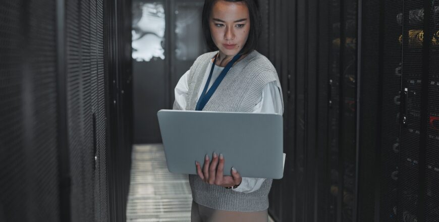 woman-with-laptop-server-room-and-it-engineer-an-2023-03-08-19-28-26-utc